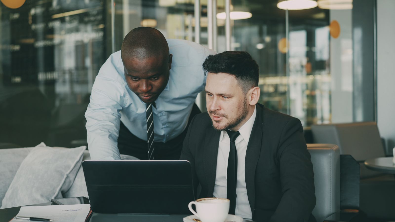 Colleagues comparing scattered spreadsheets on a laptop